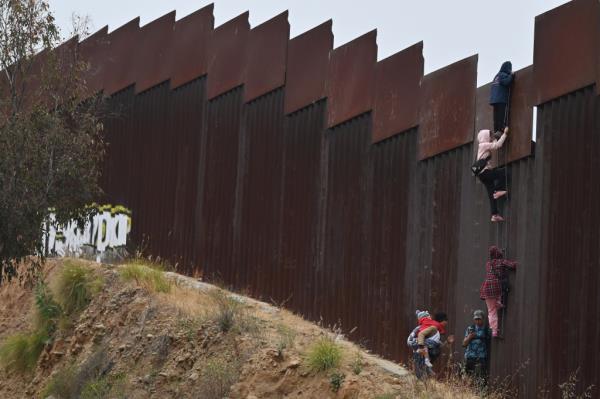 A group of adult and child migrants are smuggled at the Tijuana-San Diego border.