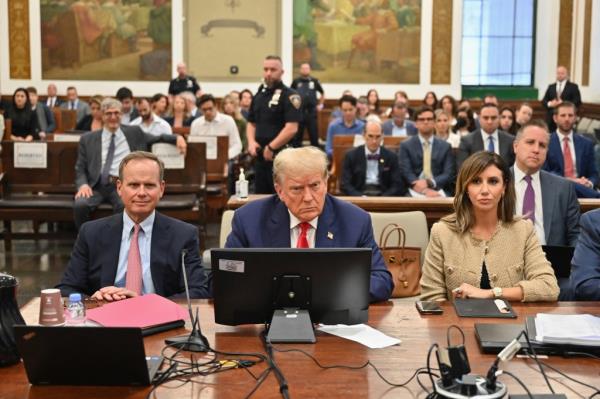 Do<em></em>nald Trump sitting at a table surrounded by his lawyers during a civil fraud trial.