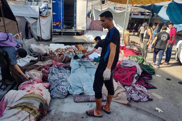 Men check the bodies of people killed in bombardment that hit a school housing displaced Palestinians, as they lie on the ground in the yard of Al-Shifa hospital in Gaza City on Nov. 10, 2023. 