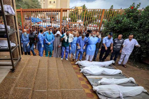 A policeman, physicians, and other men prepare to pray before some of the bodies of victims who were killed in Israeli bombardment before their burial, outside the morgue at Nasser hospital in Khan Yunis in the southern Gaza Strip on Nov. 14, 2023. 