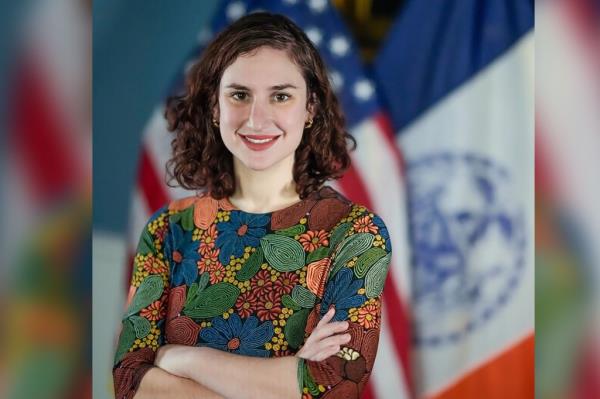 Molly Schaeffer, the city's head of migrant operations, poses for a phot in front of an American flag.
