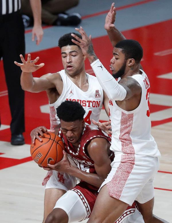 Temple Owls guard Jeremiah Williams (25) defended by Houston Cougars forward Reggie Chaney (32) and guard Quentin Grimes (24) during the first half of an NCAA men's basketball game at Fertitta Center, Tuesday, December 22, 2020, in Houston. 