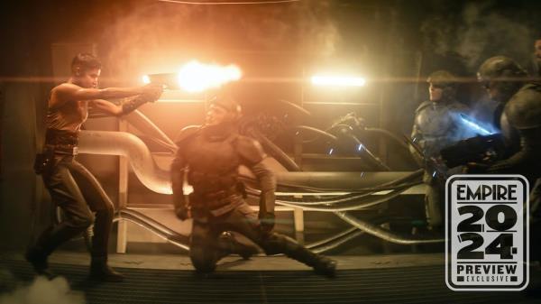 Sofia Boutella as Kora shooting a blaster at Imperium soldieres in a futuristic hallway in Rebel Moon 2.