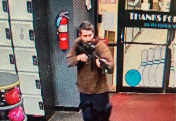A man believed to be Card is pictured at the bowling alley holding a gun.