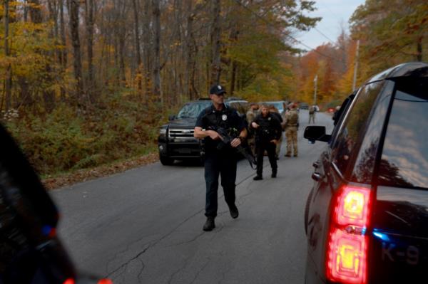 Law enforcement officials gather in the road leading to the home of the suspect being sought in co<em></em>nnection with two mass shootings on October 26, 2023 in Bowdoin, Maine.