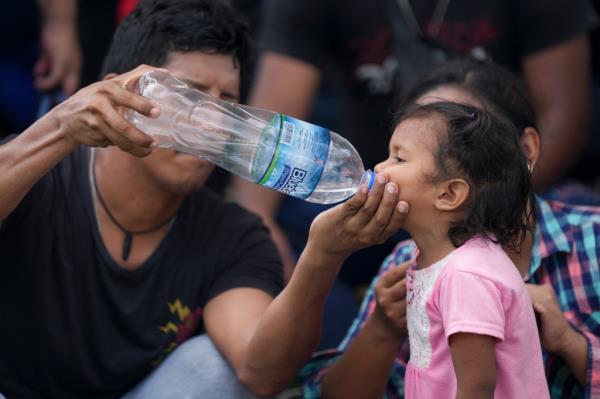 A man giving water to a child during a caravan stop.