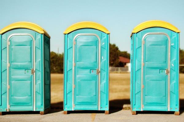 Three blue portable toilets lined up in a row.