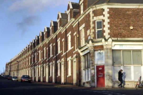 A pedestrian walks past residential properties in Newcastle