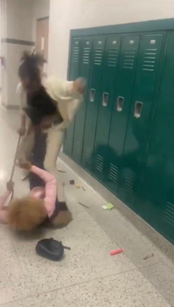 A screengrab from the video shows the teacher already on the ground clinging to the backpack.