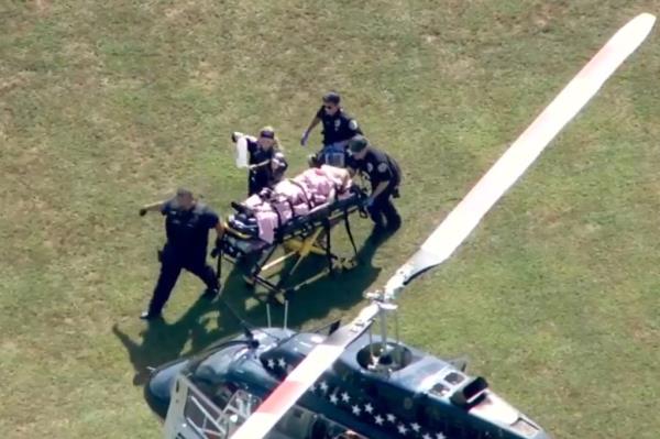 A victim on a gurney being rushed across a field.