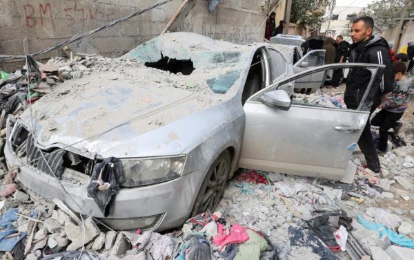 Palestinians inspect damaged vehicles at the site of an Israeli strike in Rafah near the southern Gaza Strip, on Feb. 9, 2024. 