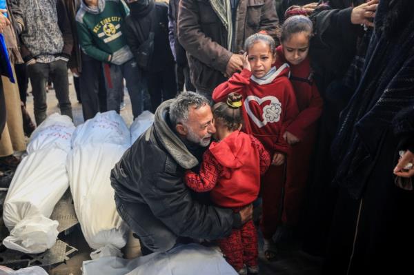 A Palestinian man hugs a little girl after identifying the bodies of of relatives killed in overnight Israeli bombardment on the southern Gaza Strip at Al-Najjar hospital on Feb. 8, 2024. 
