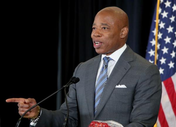 New York City Mayor Eric Adams speaking at a press conference, holding up seized illegal cannabis products