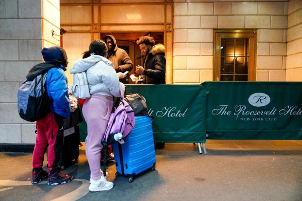 Immigrant family showing paperwork to security guards at the Roosevelt Hotel in New York City