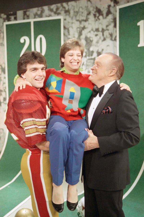 Mary Lou Retton is carried by Bob Hope and Doug Flutie.