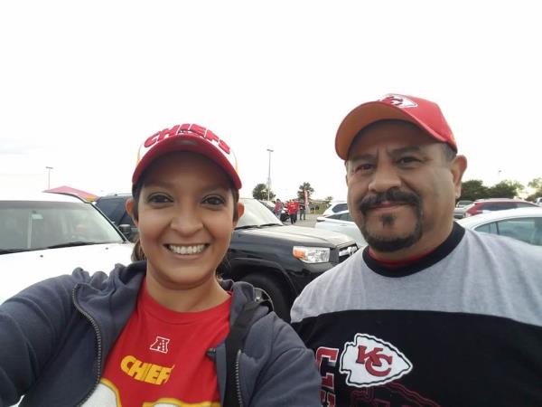 Lopez-Galvan taking selfie with man in Chiefs jersey in front of a logo backdrop