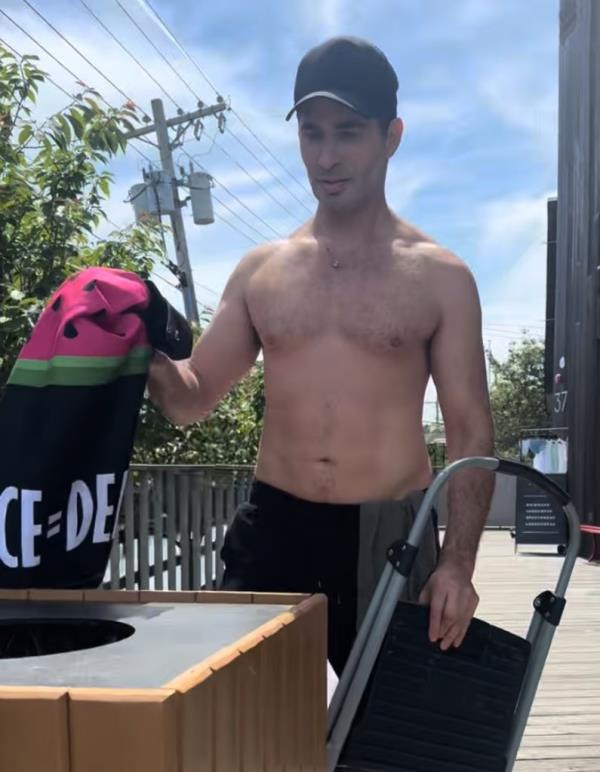 Man holding a bag and a trash can at Trailblazers Park, wher<em></em>e a flag ho<em></em>noring pro-Israel Rep. Ritchie Torrres was previously displayed