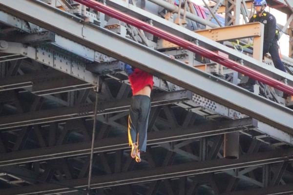 The man dangled himself from the outer beams of the Brooklyn Bridge, holding this position for nearly 20-seconds.