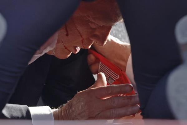 A bloodied Do<em></em>nald Trump on the ground, covered by Secret Service agents after the shooting. 
