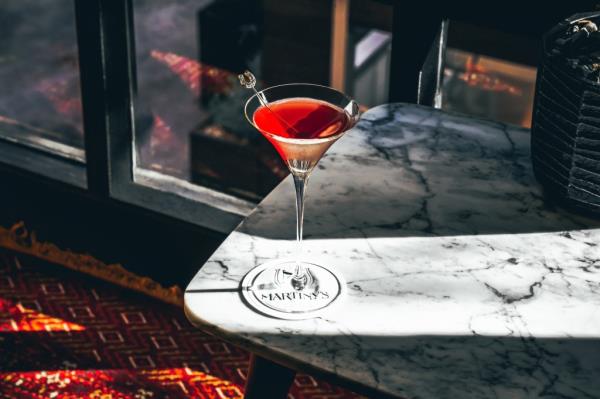 A glass of red cocktail on a marble table at Martiny's, a luxury bar in New York showcasing a fusion of old New York and Japanese precision in its service