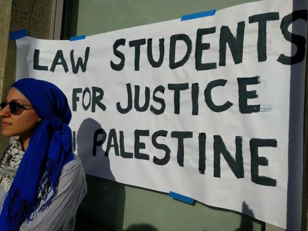 A student stands in front of a hand-painted sign reading 