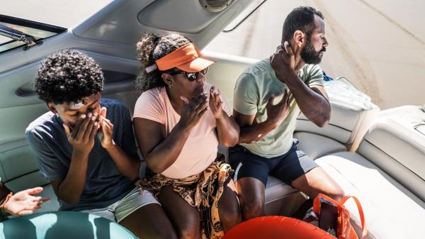 A family on a boat putting on sunscreen.