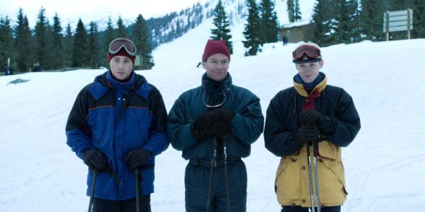 Ed McVey as Prince William, Dominic West as Prince Charles, Luther Ford as Prince Harry standing in a line in ski outfits, smiling in the snow. 
