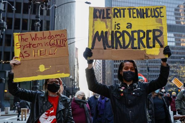 Demo<em></em>nstrators hold signs as they march in protest of the not guilty verdict in Kyle Rittenhouse's murder trial in Chicago, Illinois, November 20, 2021.