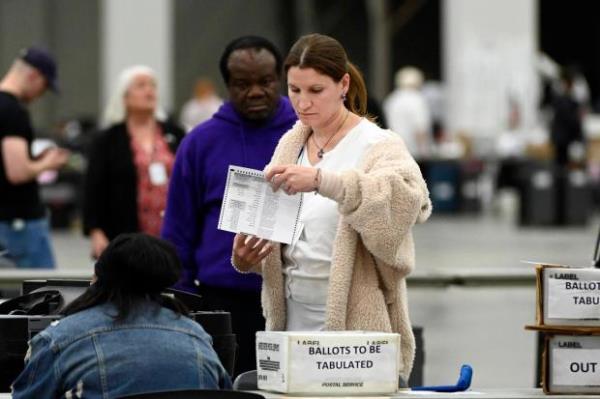 An election worker looks over an absentee voter ballot