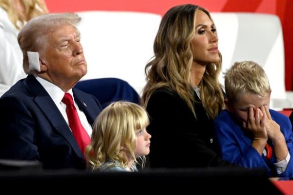 Former US president Do<em></em>nald Trump, sporting a bandage after his assassination attempt,  with his grandchildren and Lara Trump at the RNC in July.