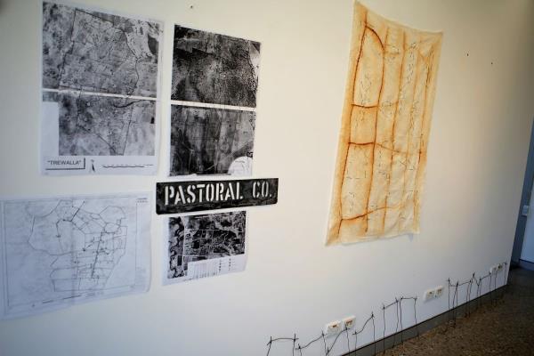 Some artworks pinned to and leaning against a white wall in an art gallery. 