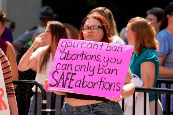 A woman holds a sign that says: 'You can't ban abortions, you cab o<em></em>nly ban SAFE abortions'.