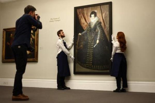 Gallery assistants position a portrait of 