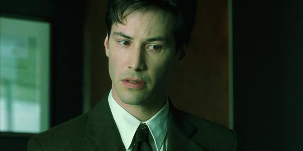 Neo (Keanu Reeves) look to the side while at an office in The Matrix
