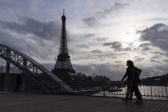 A pedestrian crosses a footbridge over the Seine in Paris.