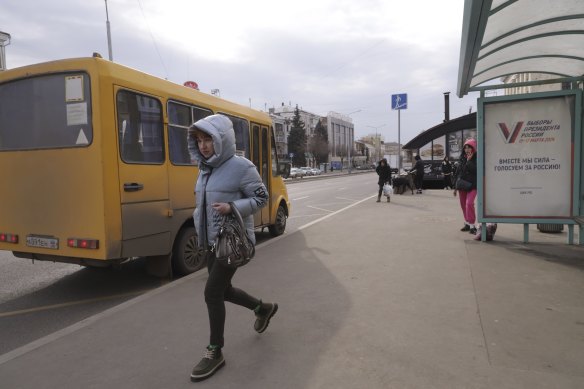 A woman walks past a billboard promoting the presidential election with a V and words in Russian: “Together we are strong, we vote for Russia!” on a bus stop in Luhansk, the capital of Russian-co<em></em>ntrolled Luhansk region, eastern Ukraine.